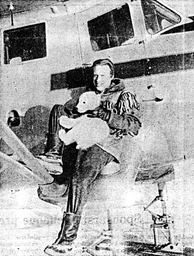 Gunnar Laurell with his Norseman bush plane, holding a baby polar bear